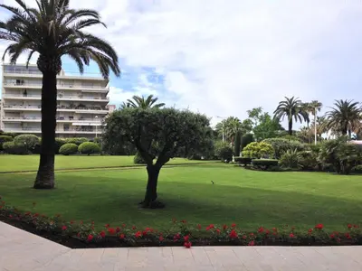 a park with palm trees and a large building at Appartement Cannes sur Croisette in Cannes