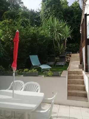 a white table and chairs with a red umbrella at Un coin de campagne en ville in Le Cannet