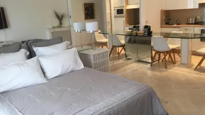 a bedroom with a bed and a table and a kitchen at CROISETTE Palais MIRAMAR FRONT DE MER in Cannes