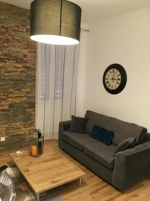 a living room with a couch and a clock on the wall at CANNES CROISETTE b in Cannes