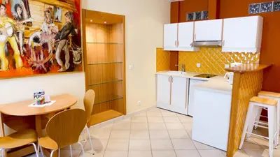 a kitchen with white cabinets and a table and chairs at Résidences Cresci in Cannes