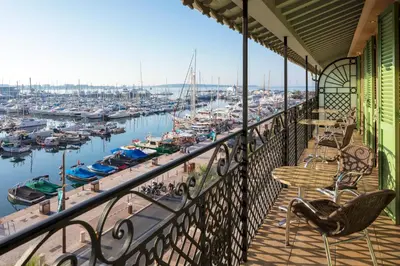 a balcony with chairs and tables and a marina at Résidences Cresci in Cannes
