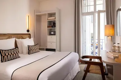 a bedroom with a bed and a desk and a window at Crisol Belle Epoque in Cannes