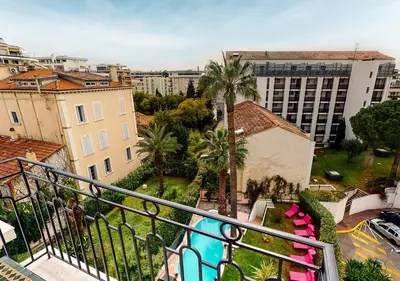 a balcony with a view of buildings and palm trees at Sun Riviera Hotel in Cannes