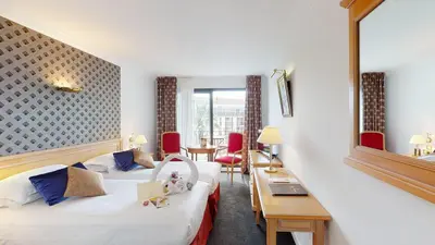 a hotel room with two beds and a desk at Sun Riviera Hotel in Cannes