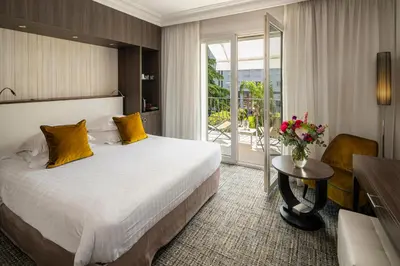 a hotel room with a bed and a table with a vase of flowers at Hôtel Le Canberra in Cannes