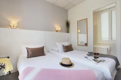 two beds in a hotel room with a hat on them at Hôtel P.L.M. in Cannes