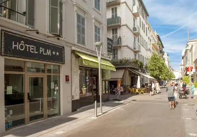 a street with buildings and people walking down the street at Hôtel P.L.M. in Cannes