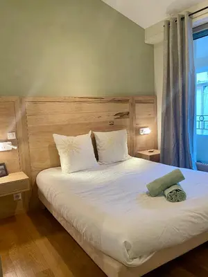 a bedroom with a bed with white sheets and a window at Duplex rénové avec balcon - Vieux Port Cannes in Cannes
