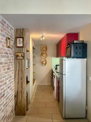 a kitchen with a white refrigerator and a brick wall at Duplex rénové avec balcon - Vieux Port Cannes in Cannes