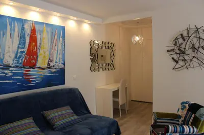 a living room with a blue couch and a painting on the wall at Central avec Jardin in Cannes