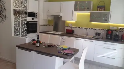a kitchen with white cabinets and a table with glasses on it at Central avec Jardin in Cannes