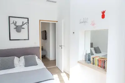 a white bedroom with a bed and a mirror at Cannes Le Chabaud in Cannes