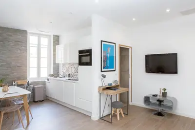 a kitchen with white cabinets and a tv on the wall at Cannes Le Chabaud in Cannes