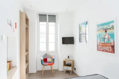 a white room with a chair and a tv at Cannes Le Chabaud in Cannes