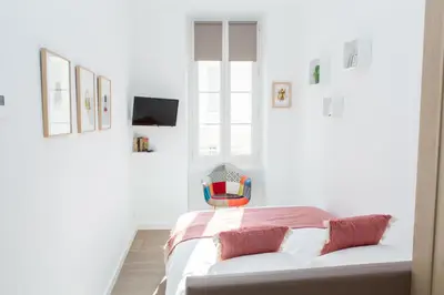 a white bedroom with a bed and a chair at Cannes Le Chabaud in Cannes