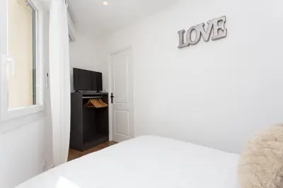 a white bedroom with a bed and a tv at Maria Sea Cannes in Cannes