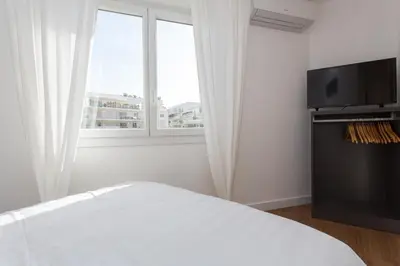 a white bedroom with a bed and a flat screen tv at Maria Sea Cannes in Cannes