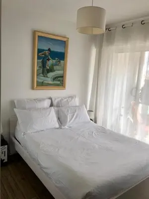a bedroom with a white bed with a painting on the wall at Central Park Apartment in Cannes
