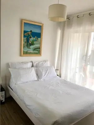 a bedroom with a white bed with a painting on the wall at Central Park Apartment in Cannes