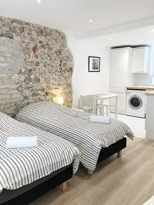 two beds in a room with a stone wall at Studio Carré d'or Cannes in Cannes
