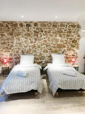 two beds in a room with a stone wall at Studio Carré d'or Cannes in Cannes