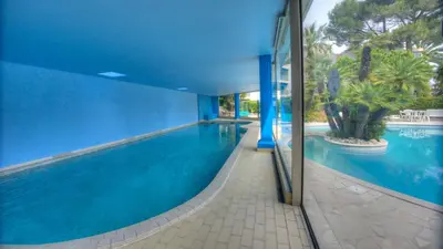 a swimming pool in a house with a blue wall at Eden Park 3 pièces 4 étoiles 100m des Plages Piscines SPA Parking in Cannes