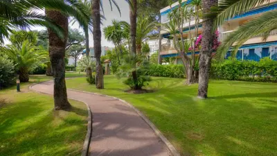 a path through a park with palm trees and a building at Eden Park 3 pièces 4 étoiles 100m des Plages Piscines SPA Parking in Cannes