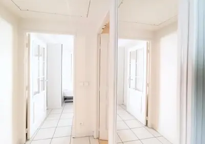 a hallway with white walls and white tile floors at Viva Riviera - Studio Jardin Florian in Cannes