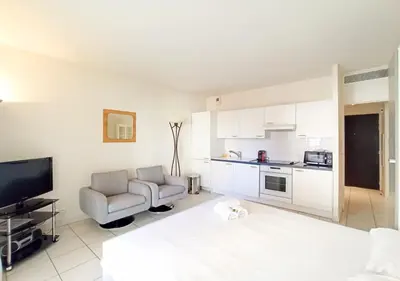 a living room with a bed and a couch and a television at Viva Riviera - Studio Jardin Florian in Cannes