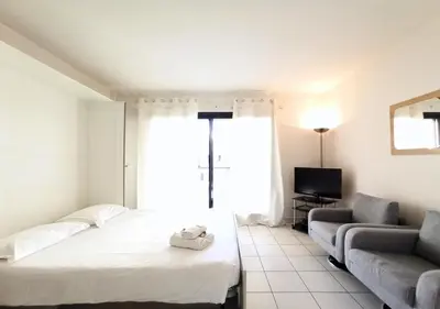 a room with a bed and a couch and a television at Viva Riviera - Studio Jardin Florian in Cannes