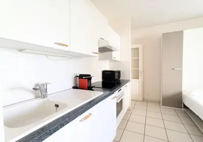 a white kitchen with a sink and a microwave at Viva Riviera - Studio Jardin Florian in Cannes