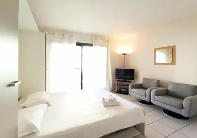 a bedroom with a bed and a couch and a television at Viva Riviera - Studio Jardin Florian in Cannes