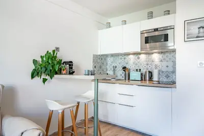 a white kitchen with white cabinets and stools at STUDIO by the croisette in Cannes
