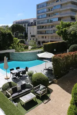 a patio with tables and chairs next to a pool at Hôtel Victoria in Cannes