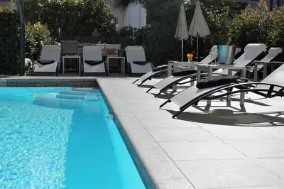 a swimming pool with chairs and a table and a table and chairs at Hôtel Victoria in Cannes