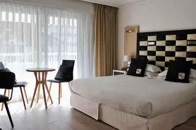 a bedroom with a large bed and a table and chairs at Hôtel Victoria in Cannes