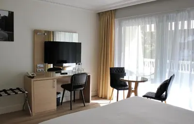 a hotel room with a bed and a table and chairs at Hôtel Victoria in Cannes