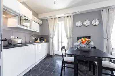 a kitchen with a table and chairs and clocks on the wall at Florella Maréchal Joffre in Cannes