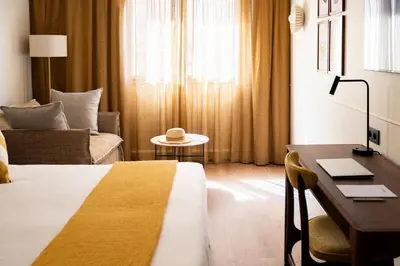 a hotel room with a bed and a desk and a couch at Hôtel Lepoussin in Cannes