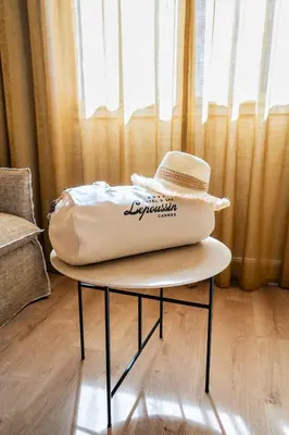 a bag on a table with a hat on it at Hôtel Lepoussin in Cannes