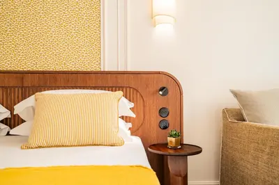 a bed with a orange and white pillow and a chair at Hôtel Lepoussin in Cannes