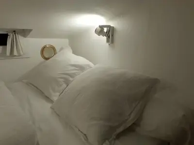 a bed with white pillows and a light on the wall at Suquet26 in Cannes