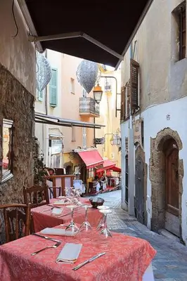 a table with red table cloths on a street at Suquet26 in Cannes