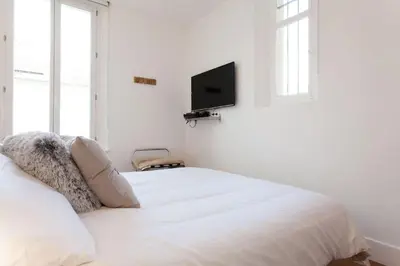 a white bedroom with a bed and a flat screen tv at Budin Sea Cannes in Cannes