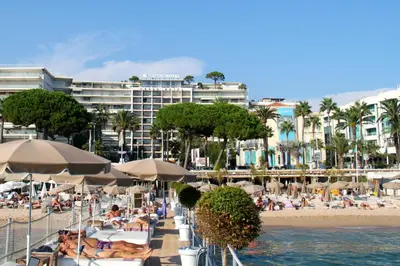 a beach with people sitting on chairs and umbrellas at From Hollywood to Bollywood 2 Bedrooms 2 Bathrooms - 1 min from Croisette&Beach, 12 Min from the Palais in Cannes