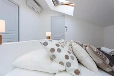 a bedroom with white walls and a bed with pillows at Teisseire Accomodations in Cannes