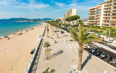 a view of a beach with palm trees and buildings at #Cannes Boccacabana Beach, Seafront, in Résid Pierre&Vacances Classé 3 Stars in Cannes