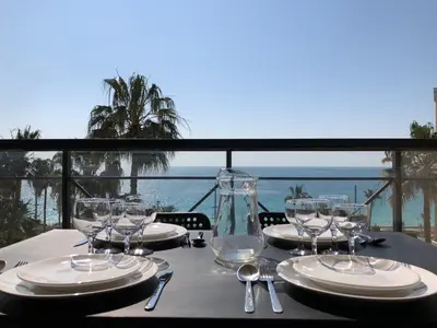 a table with plates and glasses on a table with the ocean at Appartement Vue Mer Cannes Azur in Cannes