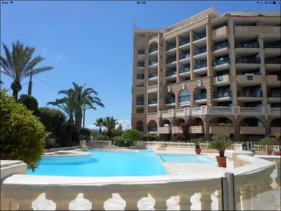 a hotel with a swimming pool in front of a building at Appartement Vue Mer Cannes Azur in Cannes